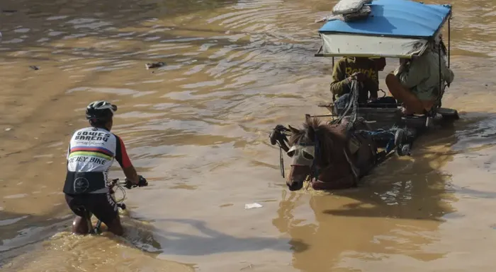 A cyclist and a horse-cart carriage pass each other in a flooded area after heavy rain caused a river overflow, submerging scores of homes in Bandung, Indonesia on March 16, 2025. Timur Matahari—AFP/Getty Images