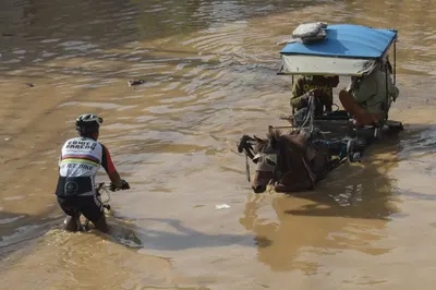 A cyclist and a horse-cart carriage pass each other in a flooded area after heavy rain caused a river overflow, submerging scores of homes in Bandung, Indonesia on March 16, 2025. Timur Matahari—AFP/Getty Images