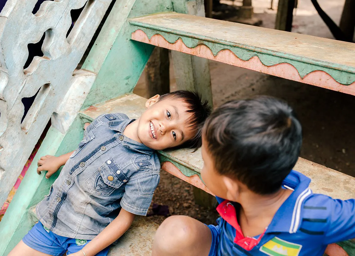 Two young boys play on the steps outside their home.
