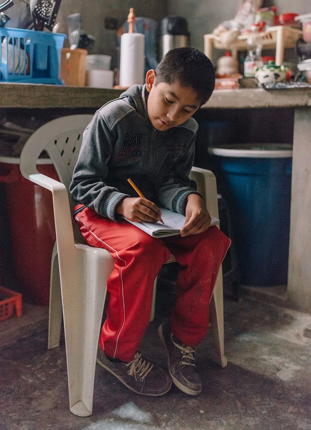 Young boy named Paulo doing homework in his kitchen in Lima, Peru.